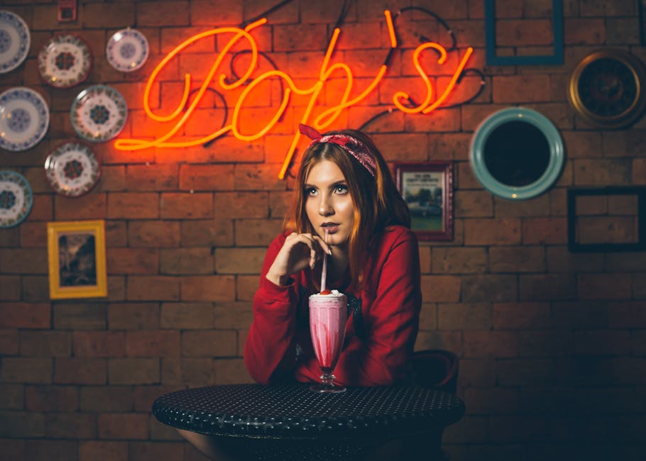 Stylish woman sipping a milkshake in a neon-lit retro diner, creating a nostalgic night out vibe.